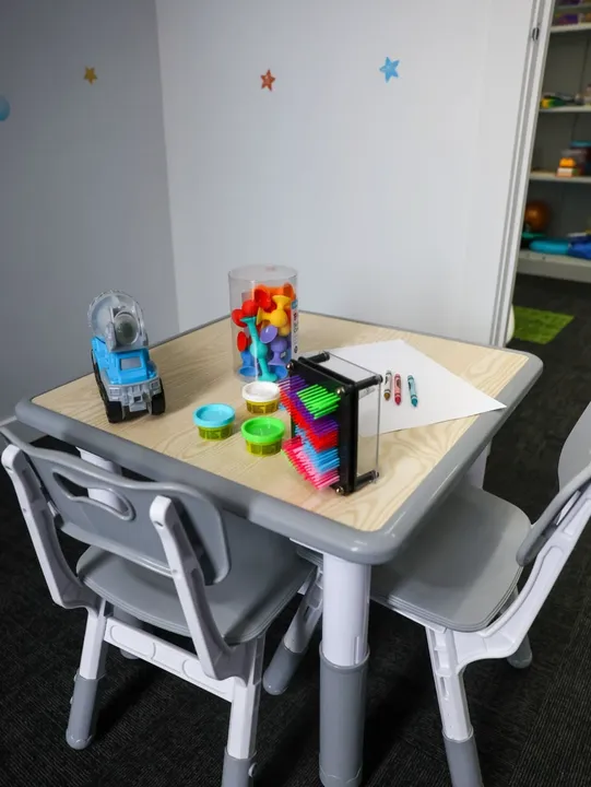 A therapy room table set up with play dough, crayons and fidget toys